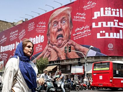 A woman walks past a large billboard pledging revenge against US President Donald Trump al