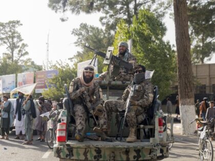 Armed Taliban fighters sit in the back of a pickup truck during celebrations for the fifth