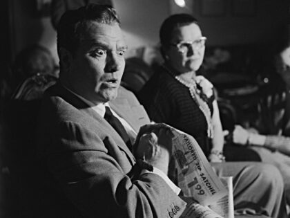 Red Skelton sits with a look of amazement on his face as he watches television with his mo