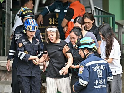 TOPSHOT - The wife (C) of a teacher who was killed in a school shooting is led to an ambul
