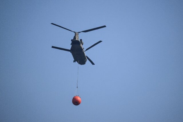 A Dutch military helicopter carries water to help fight a wildfire in Belgium's High