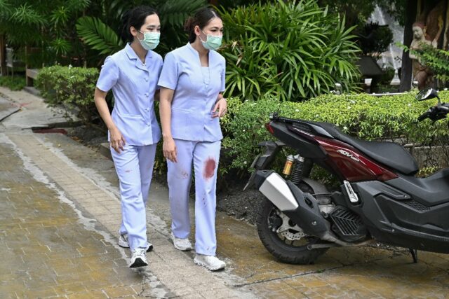 Nurses with blood stains on their scrubs leave the school following the shooting in Bang K
