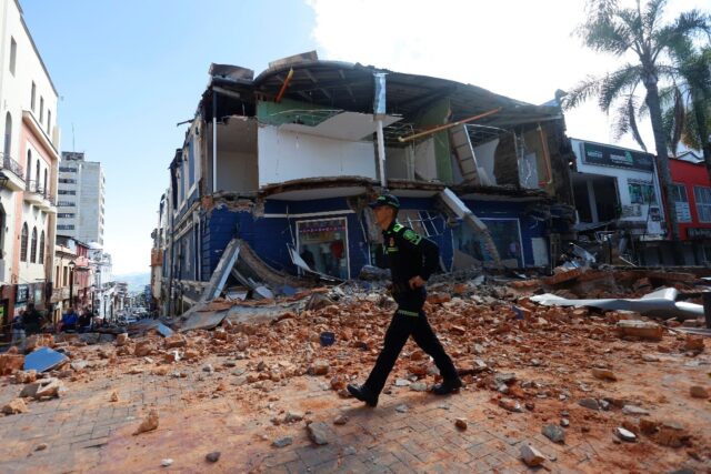 A police officer walks amid the debris of a damaged commercial store after the earthquake