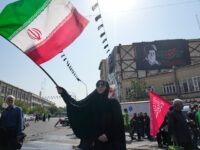 A woman waves an Iranian flag as a banner showing a portrait of the late Supreme Leader Ayatollah Ali Khamenei is seen at rear during Arbaeen rituals, which is held 40 days after Ashoura, commemorating the killing of the grandson of the Prophet Muhammad Imam Hussein and members of his family at the Battle of Karbala in 680 A.D. in Tehran, Iran, Tuesday, Aug. 4, 2026. (AP Photo/Vahid Salemi)