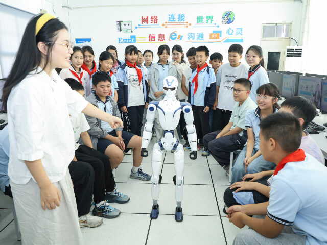 Elementary school students interact with a robot in artificial intelligence general educat