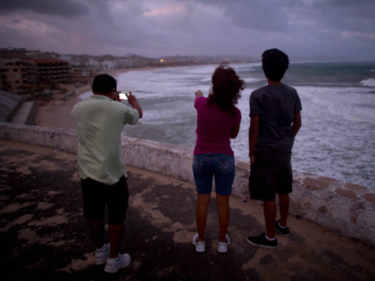 People watch and take photos from a point overlooking San Jose de los Cabos, Mexico, Satur