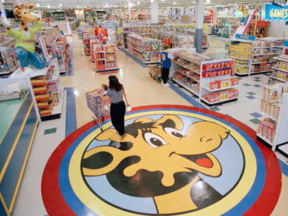 FILE- In this July 30, 1996, file photo, a woman pushes a shopping cart over a graphic of