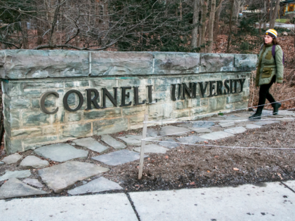 A woman walks by a Cornell University sign on the Ivy League school's campus in Ithac
