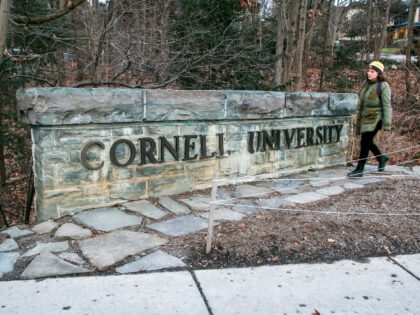 FILE - A woman walks by a Cornell University sign on the Ivy League school's campus i