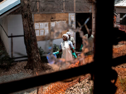 Health workers are seen through a bullet hole left in the window of an Ebola treatment cen
