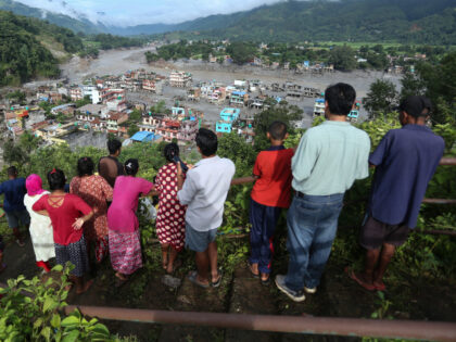 Flood victims watch from a hilltop as their homes remain submerged in Nuwakot, Nepal, on A