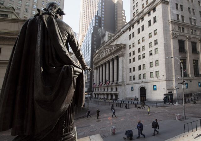US-ECONOMY-STOCKS-MARKETS People walk past the New York Stock Exchange (NYSE) and a statue of George Washington at