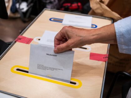 An election official casts a voter's ballot at a polling center located at Royal College o