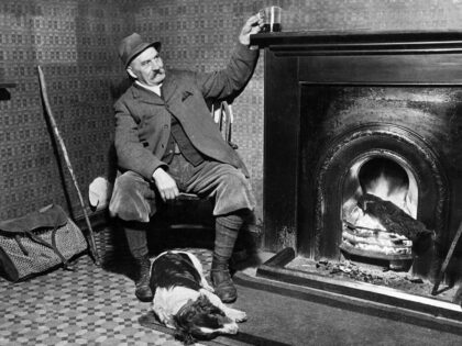 A game keeper relaxes with his drink by the fire at the Hampden Arms public house with his