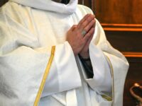 A priest wearing a white alb is praying with both hands joined in front of him in the cathedral of Valence in the Drome department in south-east France on April 2, 2026. Chrism Mass of the Catholic Church. (Photo by Nicolas Guyonnet / Hans Lucas / AFP via Getty Images)
