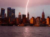 HOBOKEN, NJ - JULY 3: The Empire State Building illuminates in blue to mark the wedding of Taylor Swift as lightning strikes behind midtown Manhattan as the sun sets in New York City on July 03, 2026, as seen from Hoboken, New Jersey. (Photo by Gary Hershorn/Getty Images)
