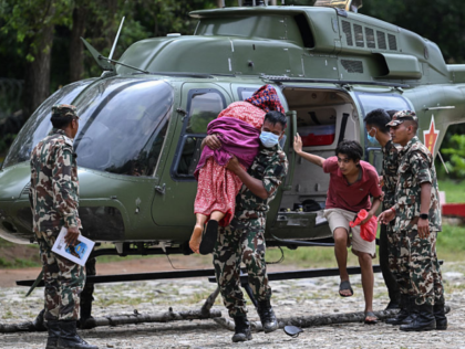 An Army personnel carries out an elderly woman from a helicopter during a rescue operation