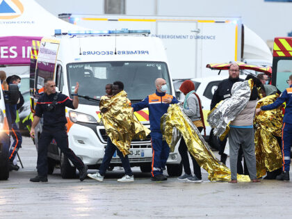 Rescuees walk with survival blankets after disembarking from an emergency response boat fo