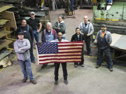 High angle view of workers and businessman holding American flag in factory