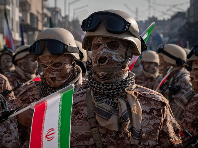 An Islamic Revolutionary Guard Corps armed personnel looks on while waiting to participate