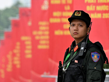 A police officer stands in front of posters for the 14th Congress of the Communist Party o