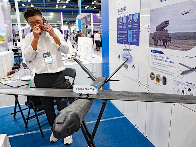 GettyImages2291482404 An exhibitor makes a phone call next to the EA040 loitering munition drone showcased at th