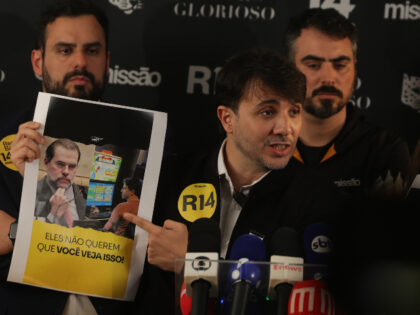 Renan Santos holds a poster featuring an image of Supreme Court Justice Dias Toffoli durin