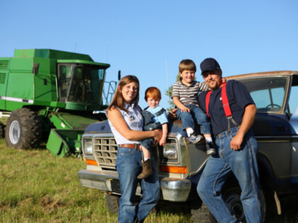 Farm family: mother, father and two sons with truck and combine. viafilms/iStock/Getty I