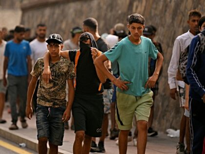 A Spanish soldier monitors a group of migrants on their way back towards the Moroccan bord