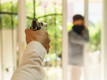 man in house pointing gun at intruder