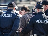Italian former communist militant Cesare Battisti (C), wanted in Rome for four murders attributed to a far-left group in the 1970s, is escorted by Italian Police officers from an airport facility into a Police car bound for Rome's Rebbibia prison, after landing in a plane coming from Bolivia and chartered by Italian authorities at Ciampino airport in Rome on January 14, 2019. - Former communist militant Cesare Battisti landed in Rome on January 14 after an international police squad tracked the Italian down and arrested him in Bolivia, ending almost four decades on the run. (Photo by Alberto PIZZOLI / AFP) (Photo credit should read ALBERTO PIZZOLI/AFP via Getty Images)