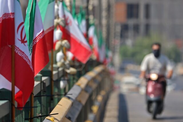 A motorist drives past Iranian flags installed along a street, a day before the funeral pr