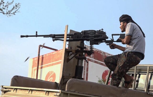 A member of the Saudi-backed Yemeni government forces fires a heavy machine gun during cla
