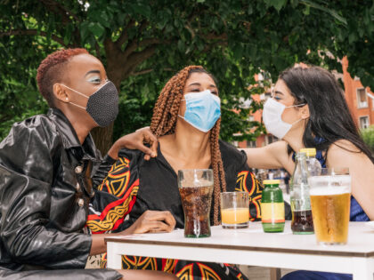 three multiracial, black, mixed raze and Caucasian friends on a bar terrace drinking a dri