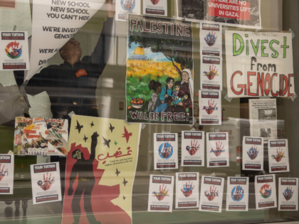 Maintenance workers clean up posters that were placed by pro-Palestinian protesters at the