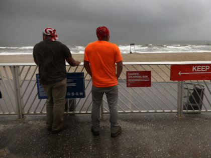 NEW YORK, NEW YORK - AUGUST 04: Two men look out at a deserted beach in Rockaway, Queens a