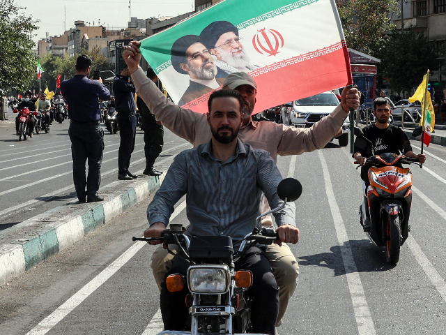 Members of Iran's Basij paramilitary force hold a flag bearing the portraits of Iran's sup