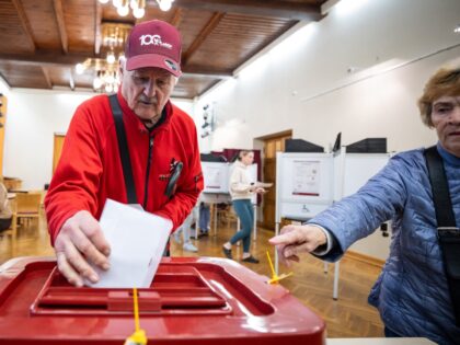 A voter casts the voting ballot into the ballot box at a polling station in Riga during th