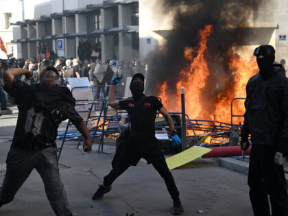 Protesters throw stones towards riot police during clashes on the sidelines of a demonstra