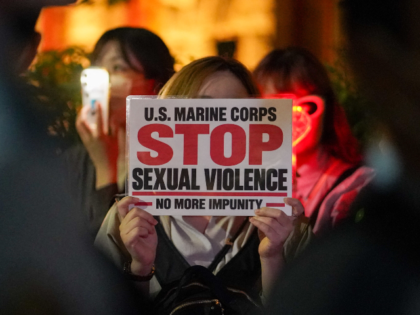 A woman holds a sign at a protest against the killing of a woman in Okinawa allegedly comm