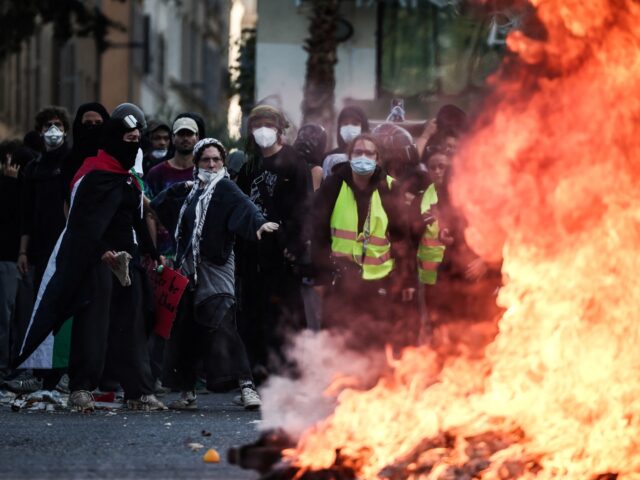 Protesters stand behind a fire during clashes prior to the start of a demonstration to pro
