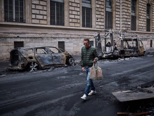 TOPSHOT - A man walks past a row of burnt out vehicles on Rue Yves Toudic destroyed after