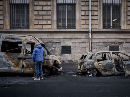 A local resident looks inside a burnt out van on Rue Yves Toudic destroyed after a weekend