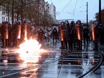French Police officers in riot gear (L) and French Gendarmes stand guard as tear gas cansi