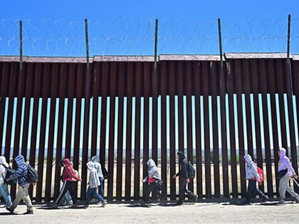 Migrants walk on the US side of the border wall in Jacumba Hot Springs, California on June