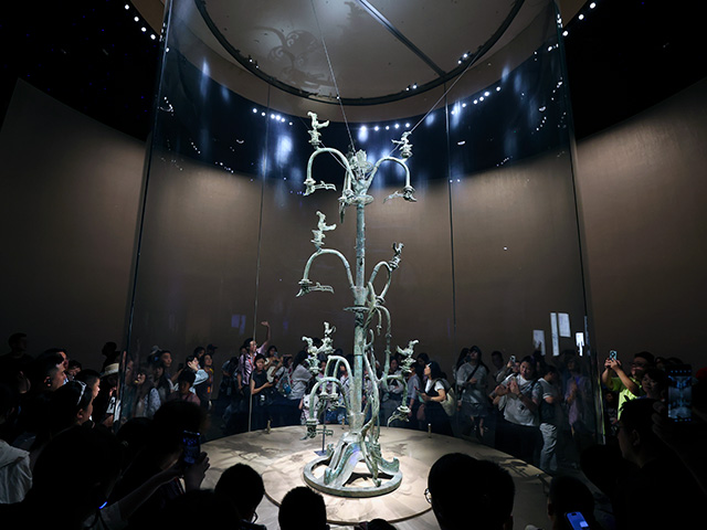 I visitatori vedono l'albero sacro in bronzo, uno dei manufatti più famosi dell'antica civiltà Shu, esposto al Museo Sanxingdui il 1° luglio 2026 a Guanghan, in Cina. L'albero in bronzo finemente lavorato, risalente a oltre 3.000 anni fa, riflette la raffinatezza artistica e spirituale della cultura Sanxingdui. Il Museo Sanxingdui ha ricevuto un totale di 6,08 milioni di visitatori nel 2025, quasi 200.000 visitatori durante il Festival di Primavera del 2026 (con una media di quasi 30.000 visitatori al giorno) e quasi 120.000 visitatori durante i cinque giorni di festa del Primo Maggio 2026. Il museo estenderà i suoi orari di apertura durante le vacanze estive del 2026. (Foto di Zhe Ji/Getty Images)
