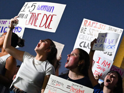 Demonstrators with the feminist-led movement Women's March hold signs and chant in protest