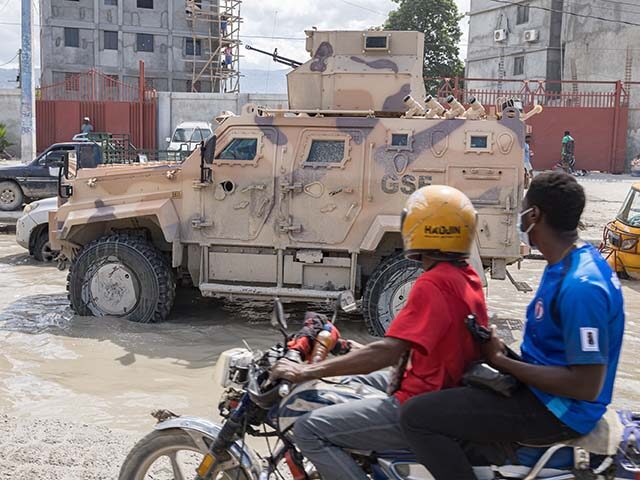 A motorcyclist rides along a street amid a traffic jam as several vehicles belonging to th