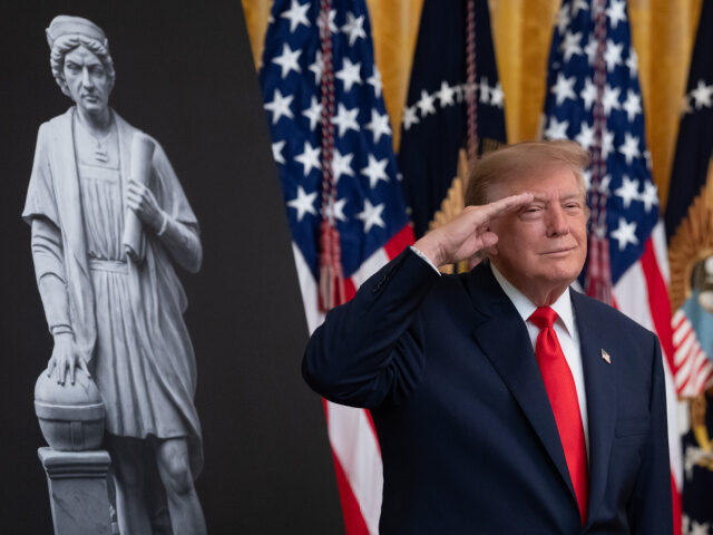 US President Donald Trump salutes during the national anthem at a Columbus Day event in th