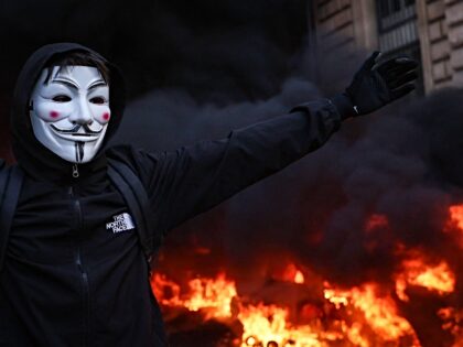 A protester wearing a Guy Fawkes (Anonymous) mask reacts during a demonstration to protest